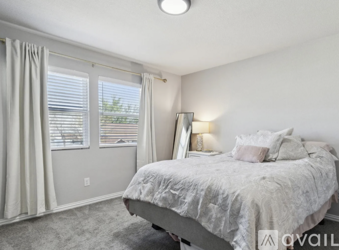 A bedroom with a large bed and a window with curtains.