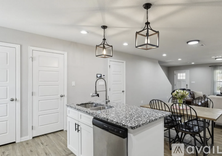 A kitchen with granite countertops and a dining table with chairs.