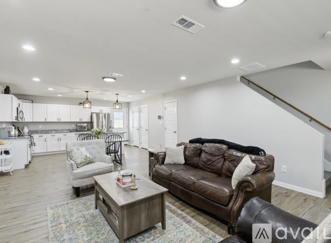 A living room with a brown leather couch and a coffee table in the middle.
