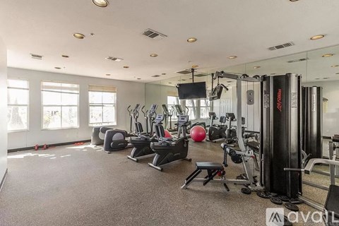A gym with a variety of equipment including treadmills, weights, and exercise machines.