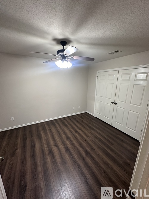 A room with a ceiling fan and wooden flooring.