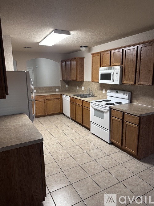 A kitchen with brown cabinets and white appliances.
