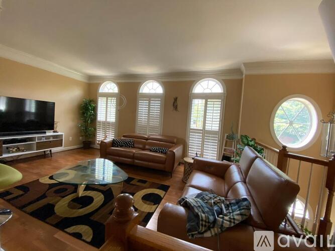A living room with a brown leather couch and a glass coffee table.