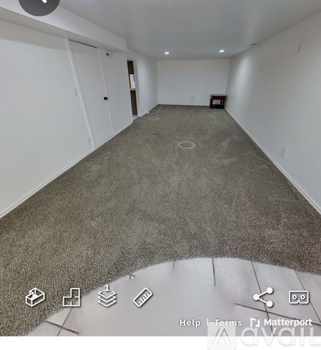 A room with a grey carpet and white walls.