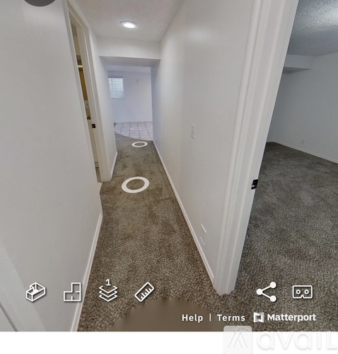 A hallway with a carpeted floor and white walls.
