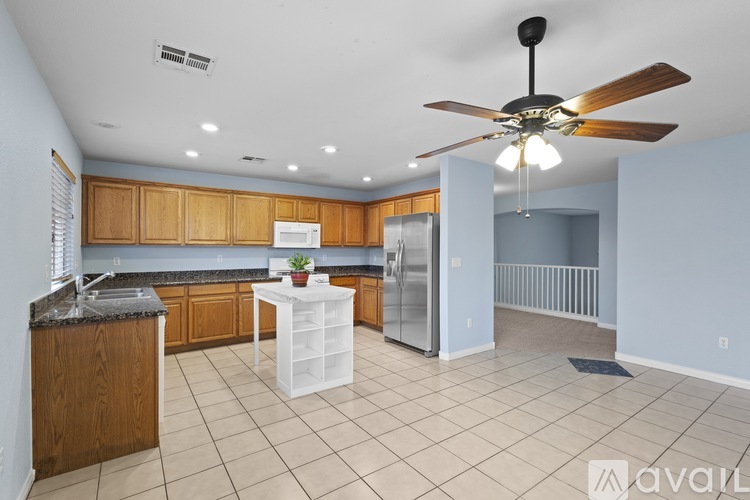 A kitchen with a ceiling fan and wooden cabinets.