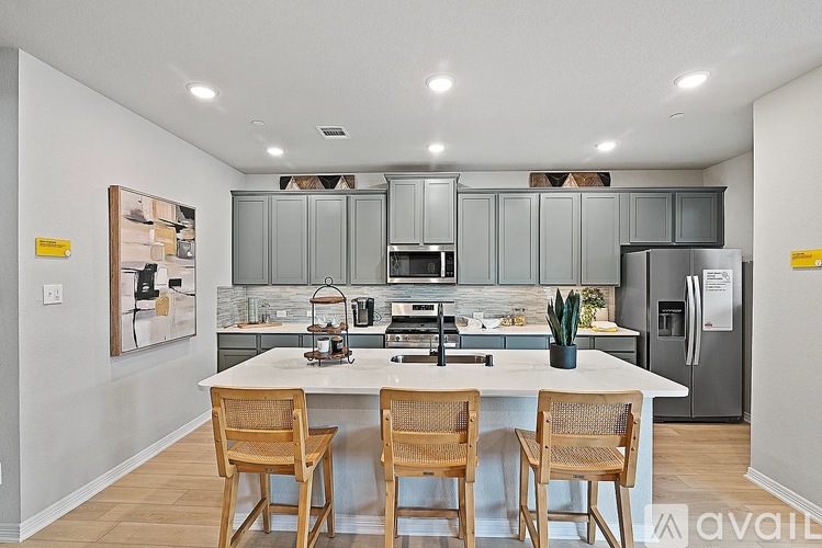 A kitchen with a white countertop and wooden chairs.