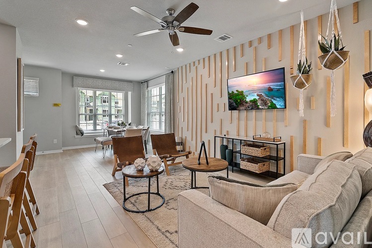 A living room with a couch, chairs, and a television on the wall.