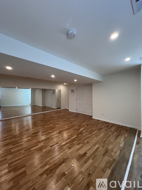 A spacious room with wooden flooring and white walls.