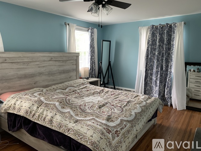 A bedroom with a bed, a dresser, and a ceiling fan.