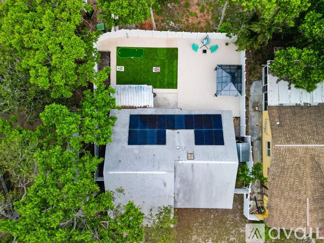 A white building with a green roof and a tennis court in front.