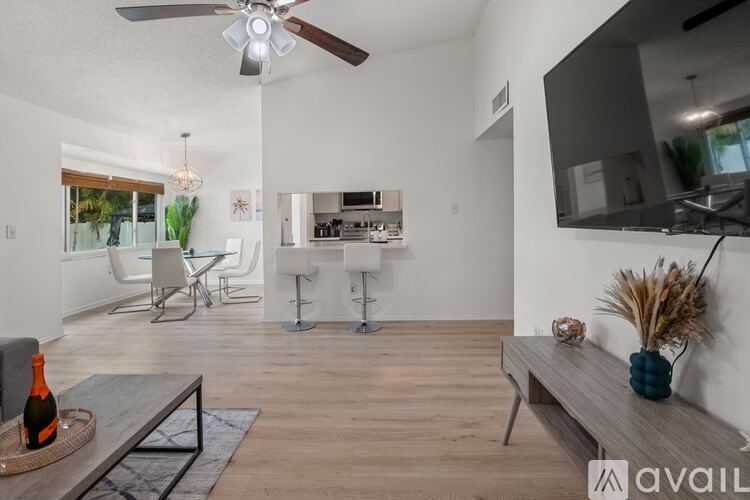 A modern living room with a ceiling fan and a dining area in the background.