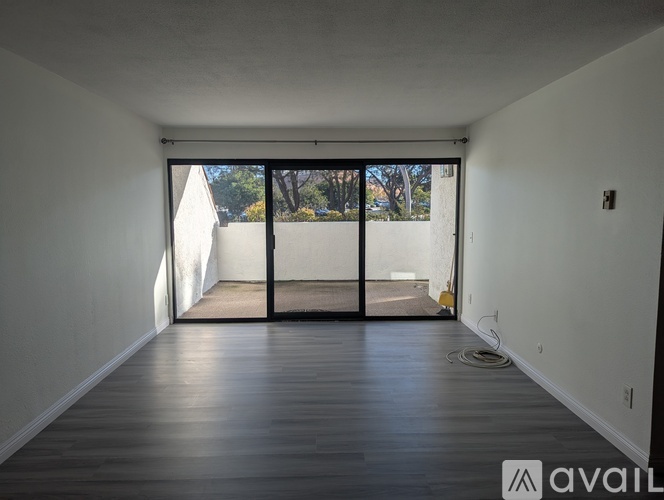 A room with wooden flooring and a sliding glass door leading to a balcony.