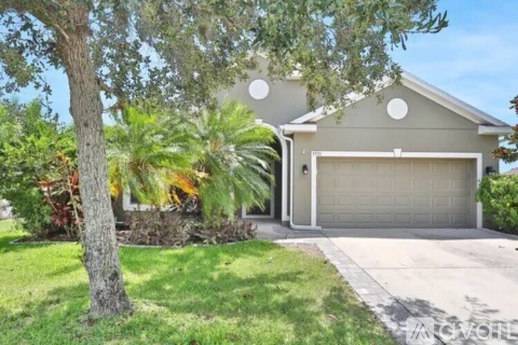 A house with a grey garage door and a tree in front.