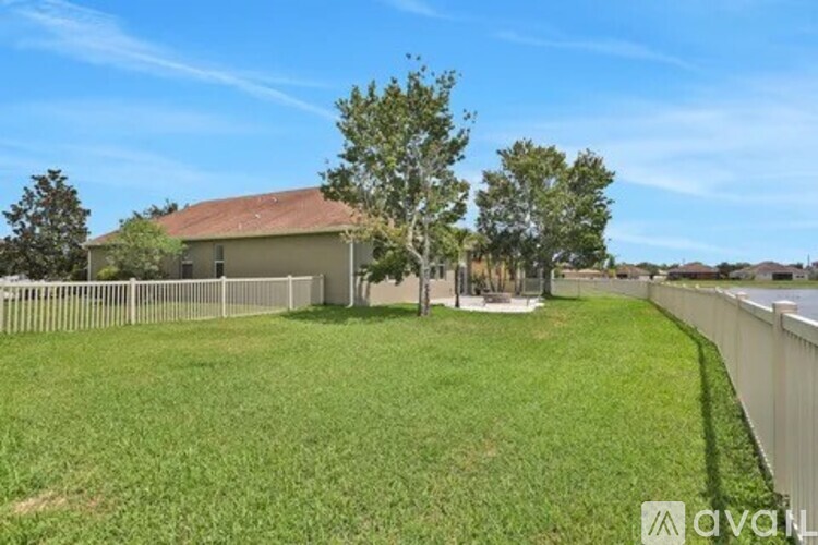 A house with a fence and a tree in front of it.