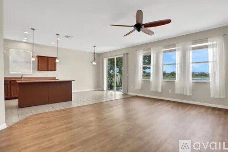 A spacious room with a wooden floor and a ceiling fan.