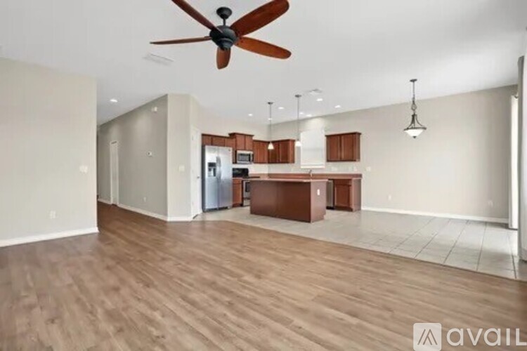 A spacious living room with a ceiling fan and hardwood flooring.