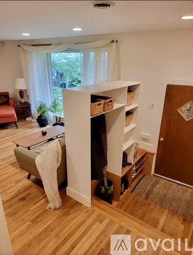 A room with a wooden floor and a large window with curtains.