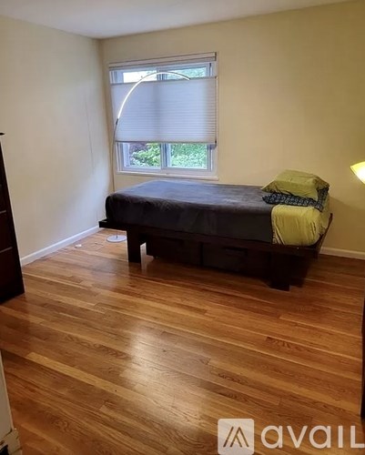 A bedroom with a bed and a window with blinds.