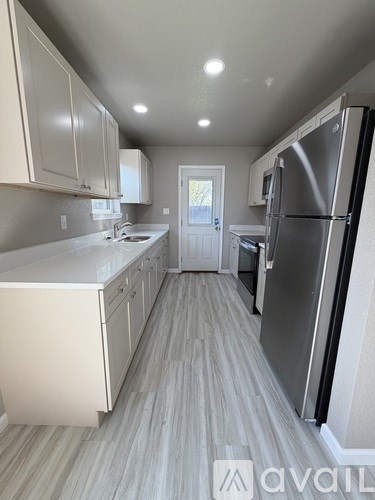 A kitchen with white cabinets and a refrigerator.