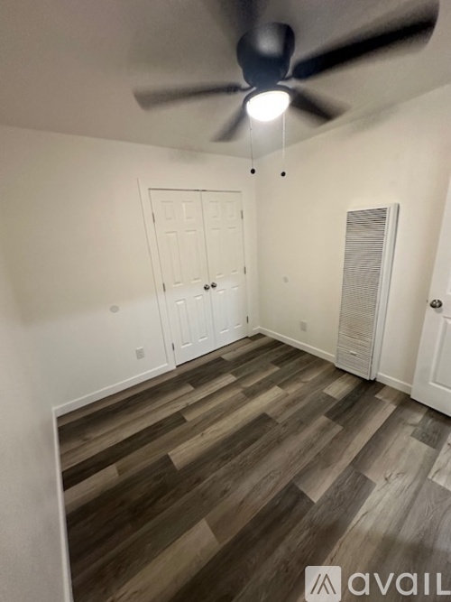 A room with a ceiling fan and wooden flooring.