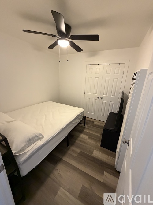 A bedroom with a bed, a ceiling fan, and a door.