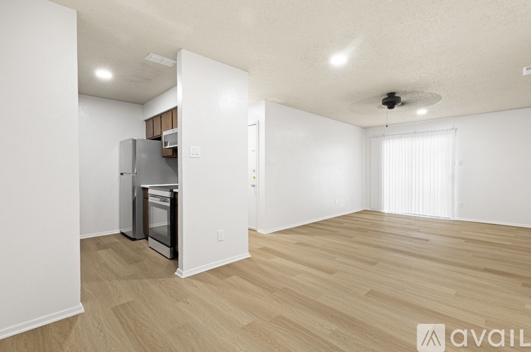A spacious room with wooden flooring and a ceiling fan.