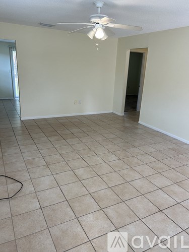 A room with a ceiling fan and tile flooring.