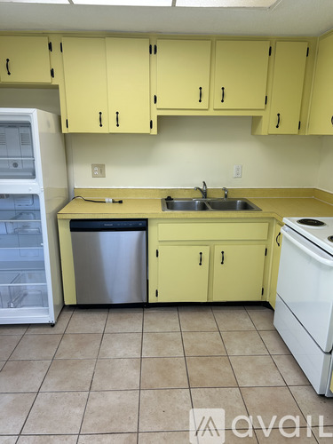 A kitchen with yellow cabinets and a white dishwasher.