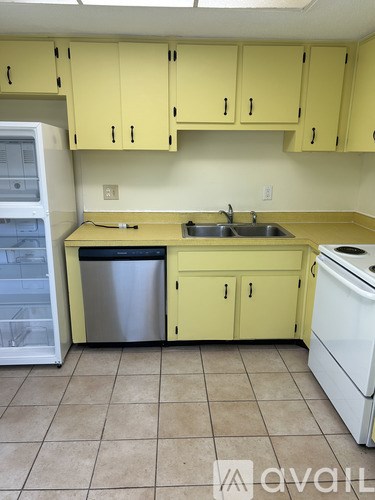 A kitchen with yellow cabinets and a white dishwasher.