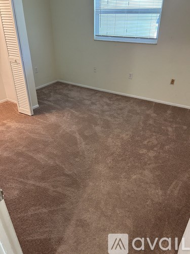 A room with a carpeted floor and a window with blinds.