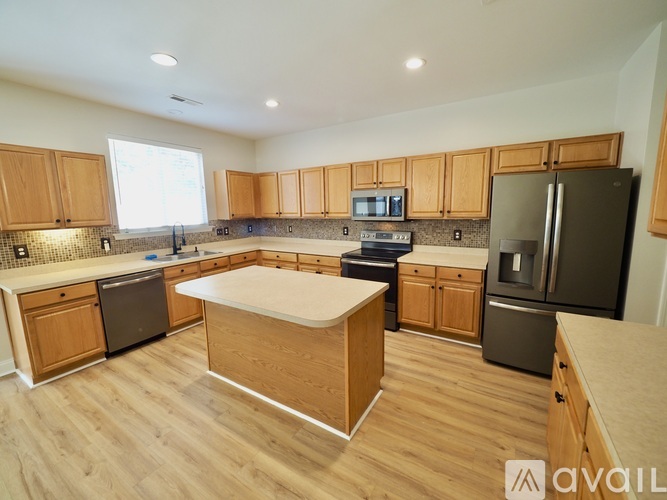 A spacious living room with wooden floors and a staircase leading to the upper level.