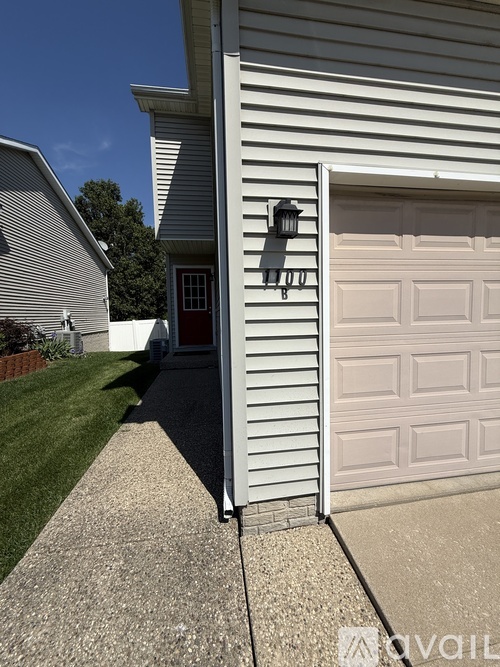 A house with a white garage door and a red door.