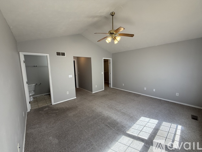 A spacious room with a ceiling fan and two doors.