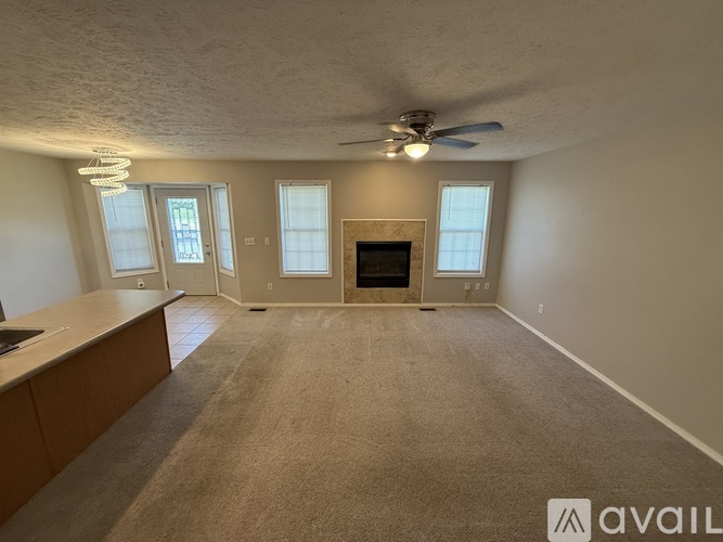 A living room with a fireplace and a fan on the ceiling.