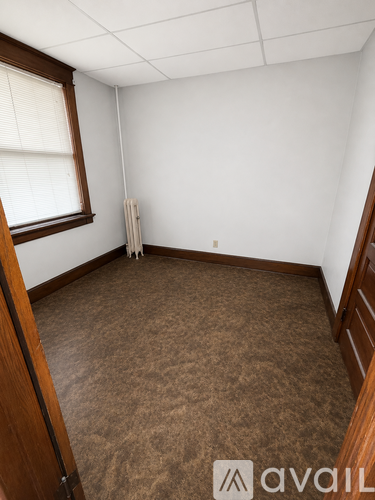 A room with brown carpet and a window with blinds.