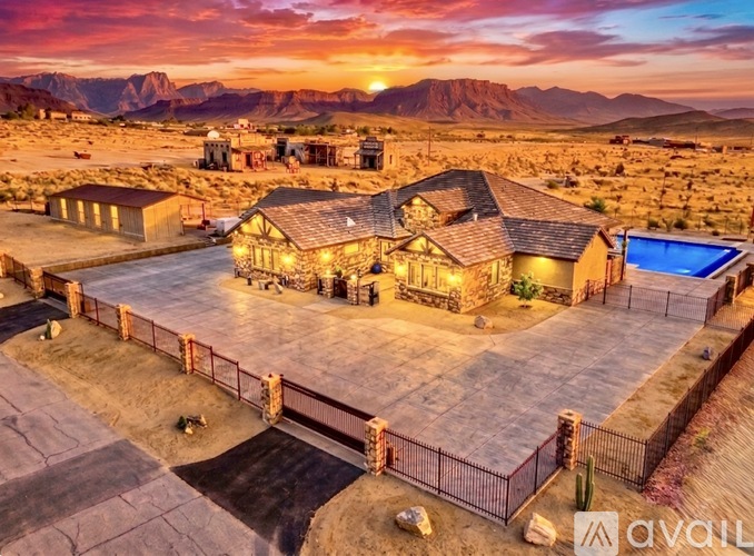 A house with a pool in the desert at sunset.
