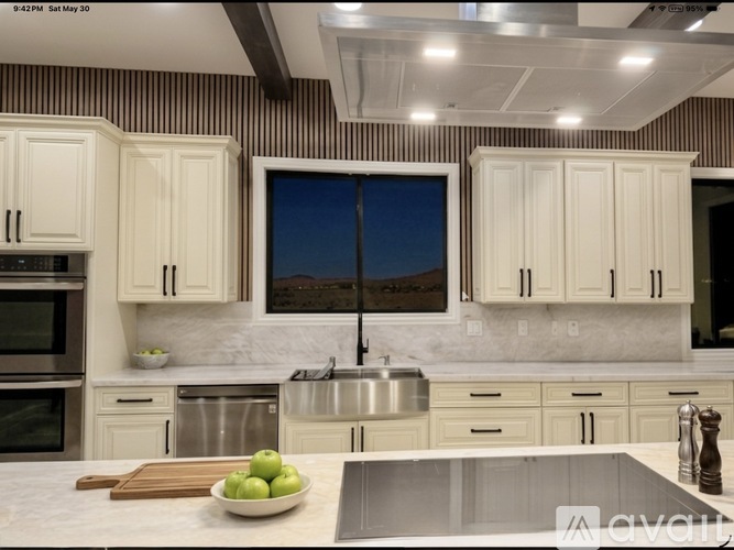 A modern kitchen with white cabinets and a wooden cutting board on the counter.