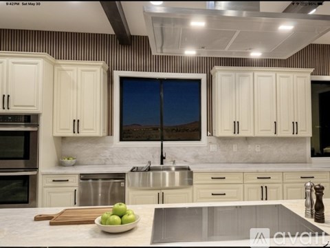A modern kitchen with white cabinets and a wooden cutting board on the counter.