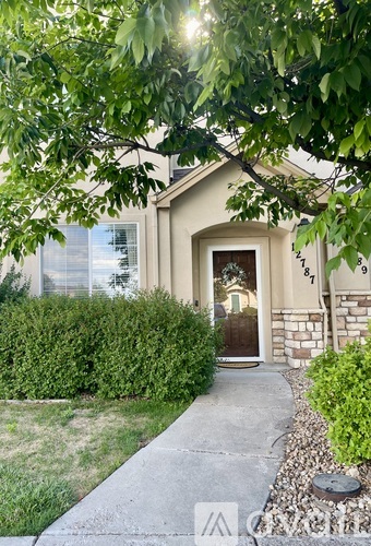 A house with a brown door is surrounded by greenery.