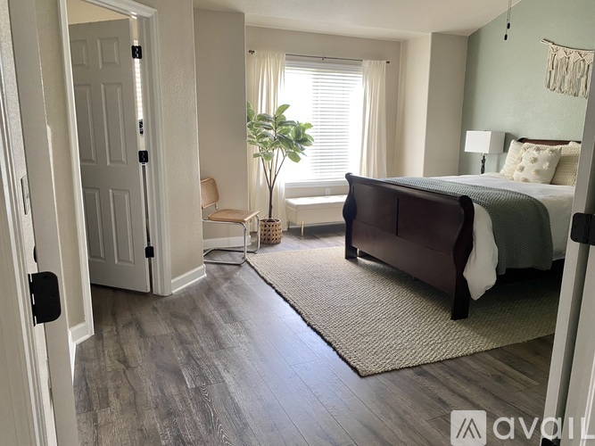 A bedroom with a large bed and a plant in the corner.