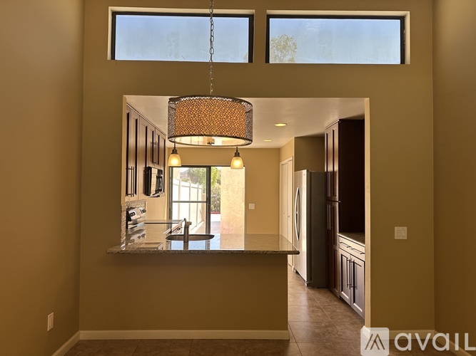 A well-lit kitchen with a large island and a hanging light fixture.
