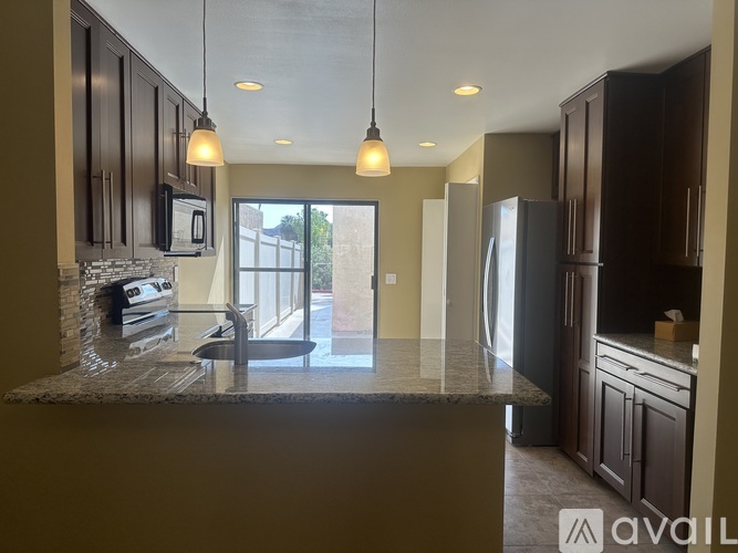 A kitchen with dark brown cabinets and a granite countertop.