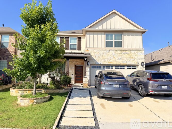 A house with a stone wall and a tree in front of it.