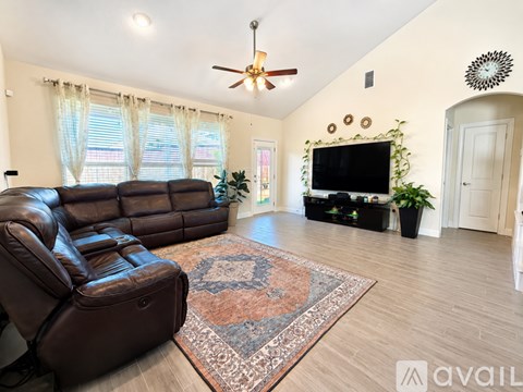 A living room with a brown leather sofa and a rug.
