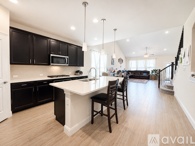 A modern kitchen with black cabinets and a white island.