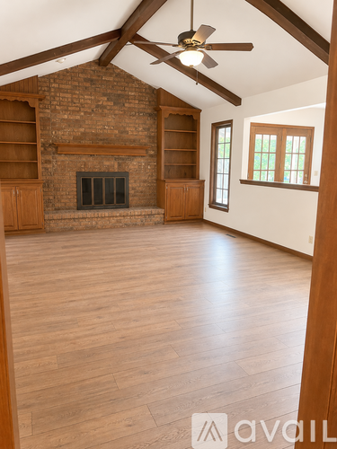 A room with a brick fireplace and wooden floors.