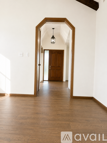A hallway with wooden floors and a brown door.