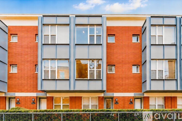 A modern apartment building with red brick and grey panels.