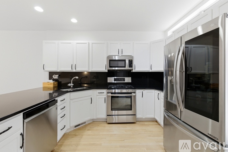 A kitchen with white cabinets and black countertops.